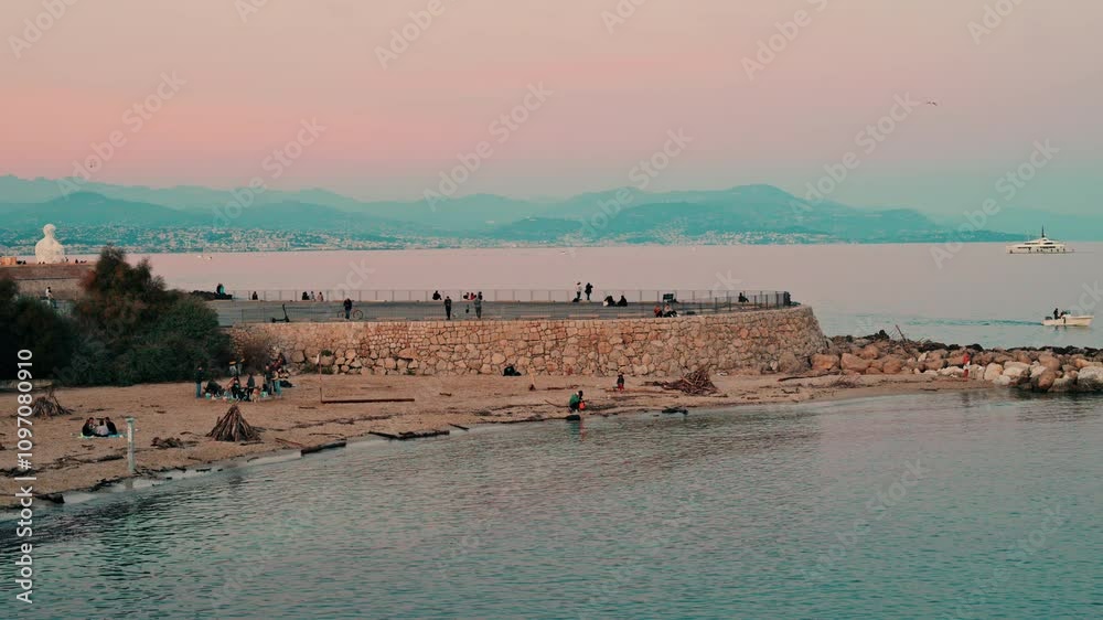 Scenic coastal view of people at a beach Antibes, France at sunset Scenic coastal view of people at a beach Antibes, France at sunset