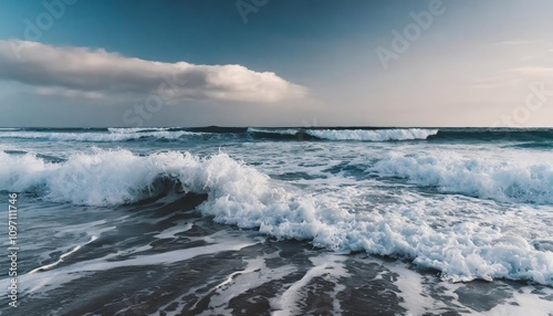 A serene view of foamy ocean waves rolling onto a sandy shore under a vibrant blue sky, capturing the dynamic motion and peaceful rhythm of the sea with vivid detail and natural beauty.