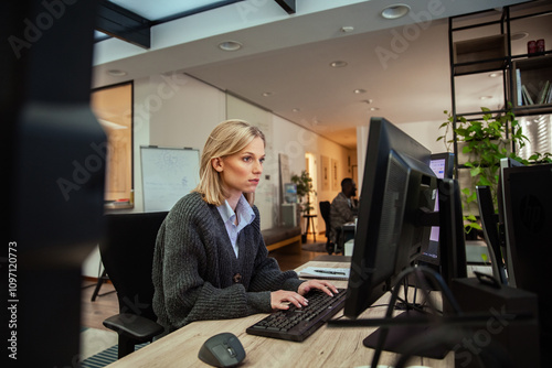 Focused woman working at dual monitors in modern office setting