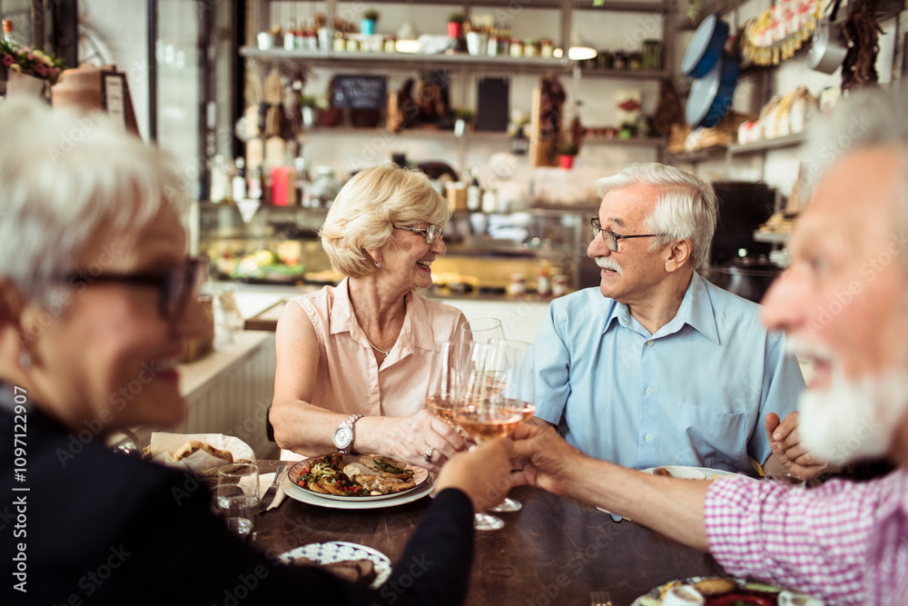 Happy senior friends eating at a cozy bistro together Happy senior friends eating at a cozy bistro together