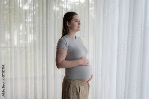 Portrait of pregnant gen z woman standing near window holds hands on her belly at home. Pregnancy, motherhood, expectation and tenderness concept Free Download Portrait of pregnant gen z woman standing near window holds hands on her belly at home. Pregnancy, motherhood, expectation and tenderness concept - GFXLoad