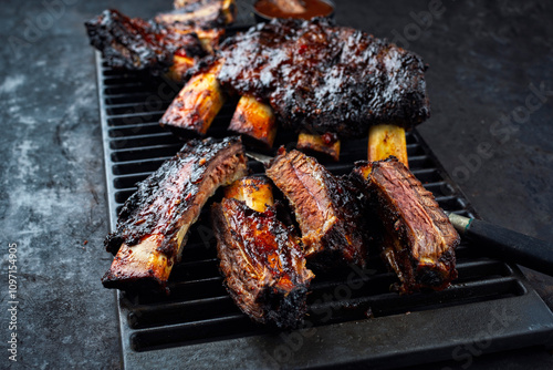 Traditional barbecue burnt chuck beef ribs marinated with spicy rub and served as close-up on a rustic cast iron grillage photo