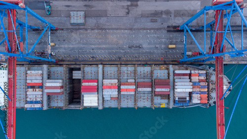 Aerial view of vibrant container ship docked at bustling port with colorful containers, cranes, and tranquil water.  global shipping, logistics, and maritime commerce concepts.