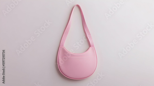 A pale pink, small, crescent-shaped handbag with a single shoulder strap, photographed against a white background. photo