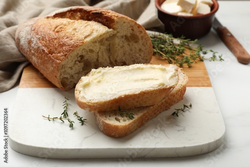 Fresh bread with butter and thyme on white table, closeup