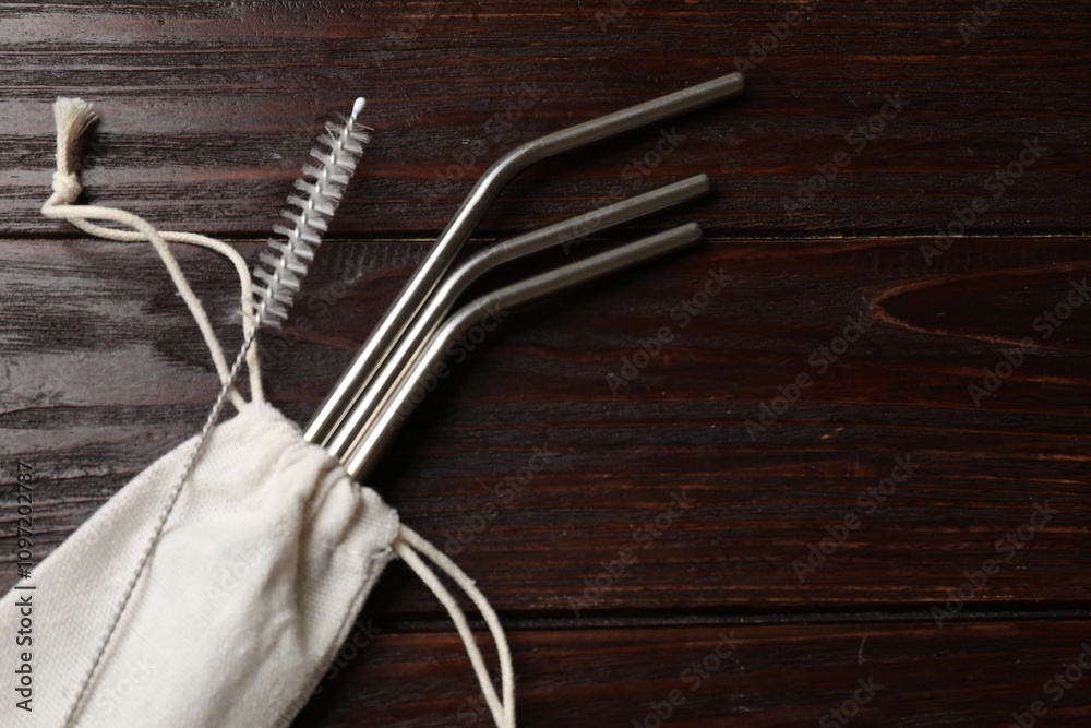 Metal drinking straws, cleaning brush and bag on wooden table, top view. Space for text Metal drinking straws, cleaning brush and bag on wooden table, top view. Space for text