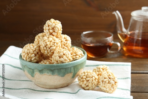 Delicious puffed rice balls in bowl and tea on wooden table, closeup photo