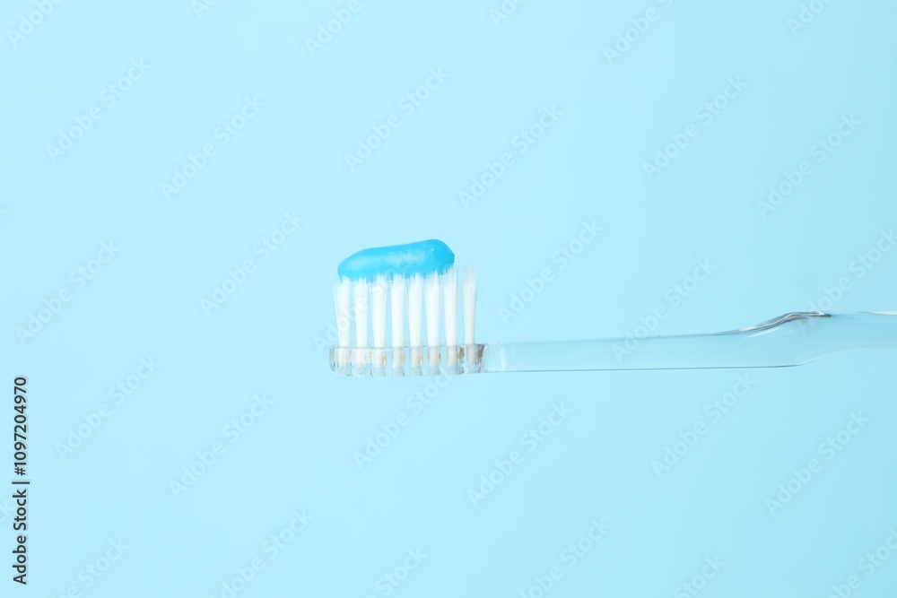 Toothbrush with toothpaste in air on light blue background, closeup. Space for text Toothbrush with toothpaste in air on light blue background, closeup. Space for text
