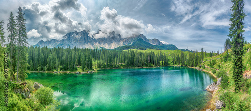 The emerald green Lake Carezza reflecting Latemar mountain, Dolomites, Italy