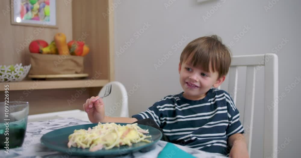 Young boy interacting with parents at dining table, holding fork over pasta plate, smiling and laughing, cheerful family moment during lunch, focus on connection Young boy interacting with parents at dining table, holding fork over pasta plate, smiling and laughing, cheerful family moment during lunch, focus on connection