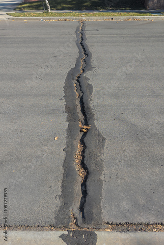 Crack in asphalt road with evidence of repair photo