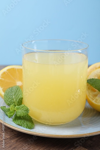 Glass of lemon juice and fresh fruits on wooden table, closeup