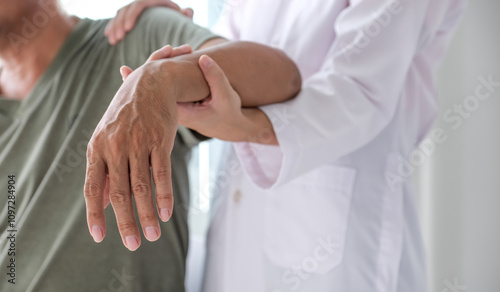 Female doctor hand rehab physical therapy by extending the pain shoulder of a patient. treatment with stretch exercises