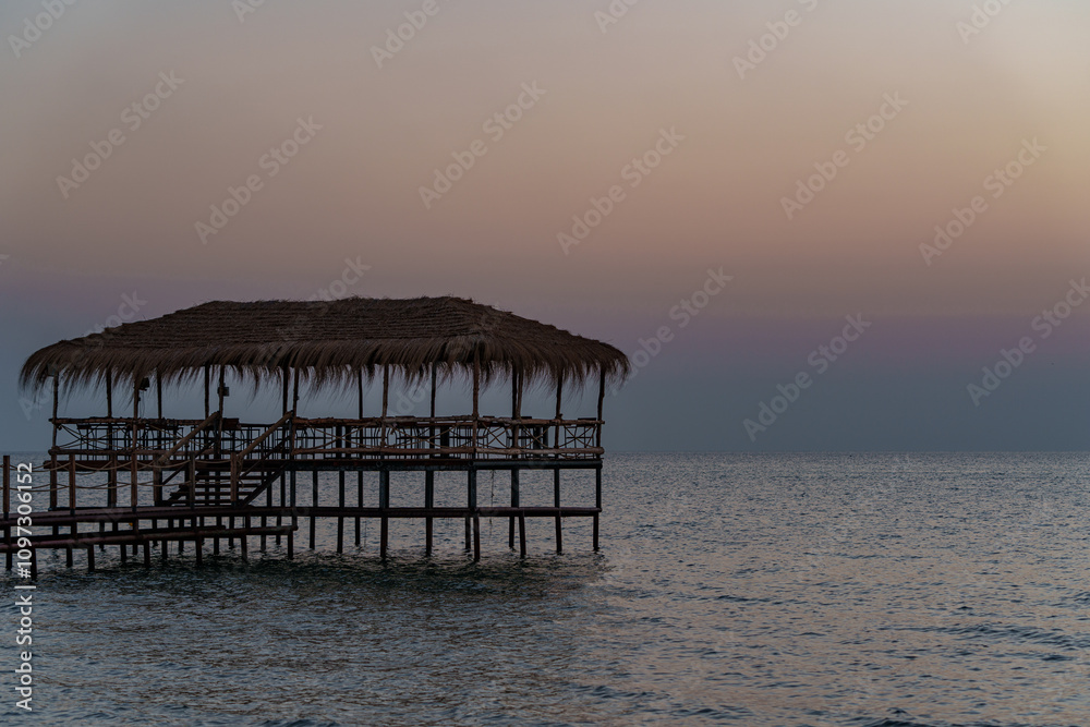 Obraz premium A beautiful view of the sunrise, sunset over the sea horizon with a pier in the foreground