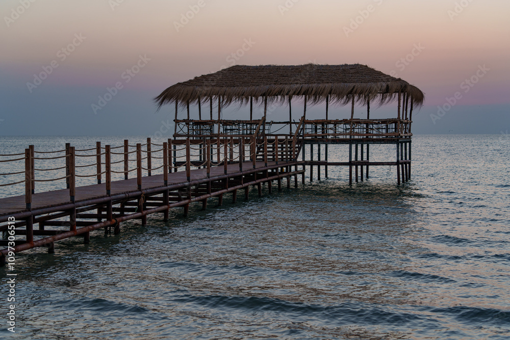 Obraz premium A beautiful view of the sunrise, sunset over the sea horizon with a pier in the foreground