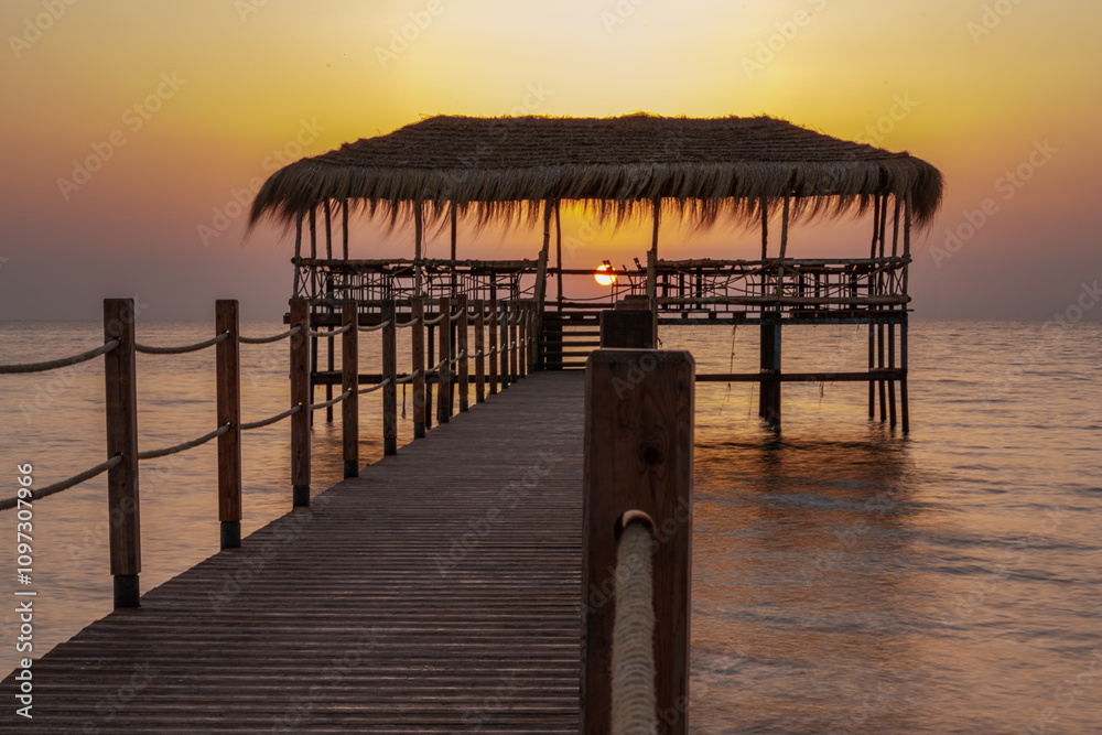 Fototapeta premium A beautiful view of the sunrise, sunset over the sea horizon with a pier in the foreground