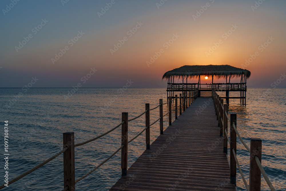 A beautiful view of the sunrise, sunset over the sea horizon with a pier in the foreground A beautiful view of the sunrise, sunset over the sea horizon with a pier in the foreground
