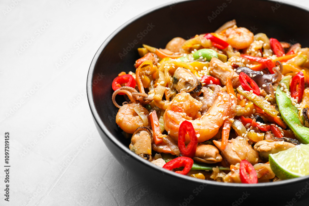 Stir-fry sea food in bowl on light grey table, closeup Stir-fry sea food in bowl on light grey table, closeup
