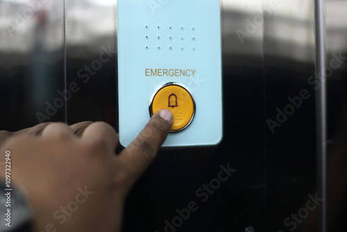Close up of a hand pressing the emergency button in an elevator