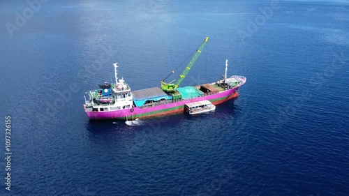 Drone view of a large ship in a calm ocean on a sunny day.