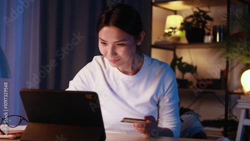Pretty young asian woman paying with credit card on tablet computer at home Happy customer doing payments online shopping in internet store and receiving cashback at late night Easy pay concept