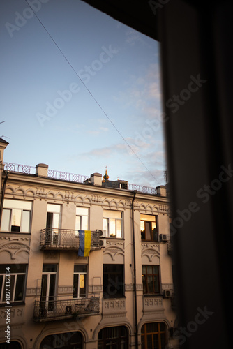 Window view on Andriyivsky Uzviz in Kyiv, Ukraine. Ukrainian flag hangs on a balcony. Sunset light. photo