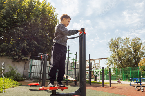 Young Boy Exercising on Outdoor Stepper Equipment in Public Playground During Daytime Physical Activity and Fitness Training