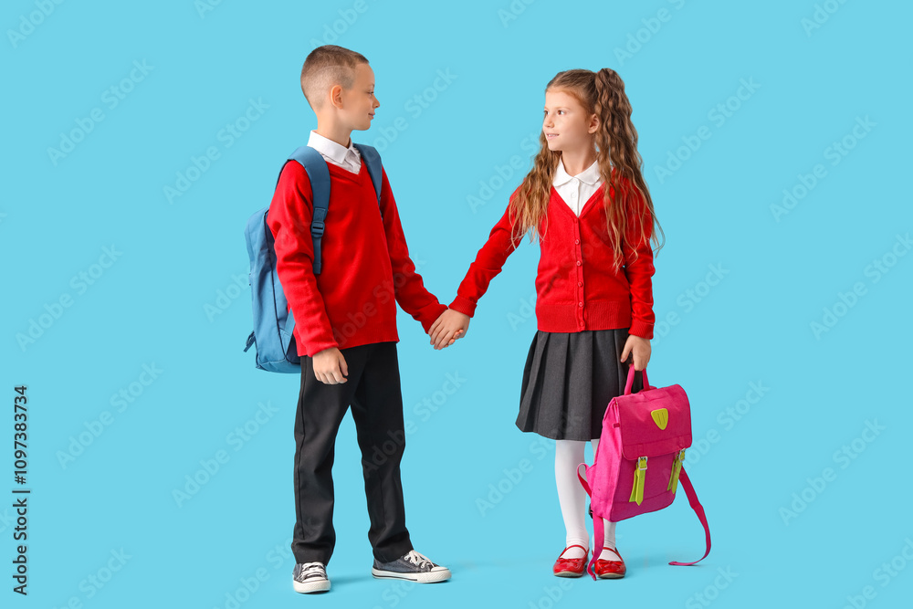 Little pupils with backpacks holding hands on blue background Little pupils with backpacks holding hands on blue background