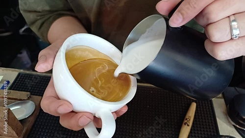 Coffee shop barista making latte art, home barista pouring cappuccino, morning coffee with milk, 
professional coffee art. 
