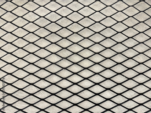 Industrial black expanded metal in diamond shape with light concrete background.