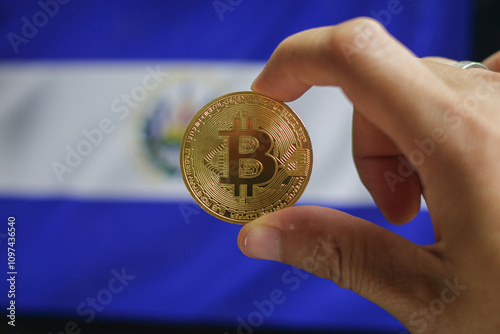 Holds a physical version of Bitcoin and the flag of El Salvador. Conceptual diagram of El Salvador's cryptocurrency and blockchain technology. Double exposure creative bitcoin symbol hologram. photo