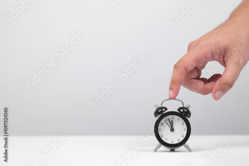 A hand adjusting an alarm clock, symbolizing time management and the importance of punctuality in daily life. photo