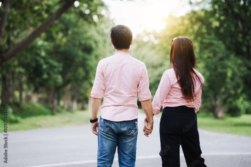 A young couple walks hand in hand, shoulder-hugging romantically in a lush green forest. Smiling happily, they express deep love, trust, and stability, embracing the beauty of nature together A young couple walks hand in hand, shoulder-hugging romantically in a lush green forest. Smiling happily, they express deep love, trust, and stability, embracing the beauty of nature together