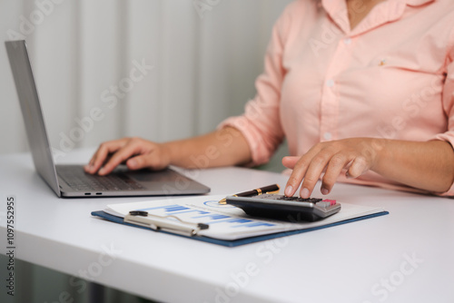 A close-up of a businesswoman working on a laptop in an office. As an accountant, she records financial data, verifies documents, manages income and expenses, ensuring accurate financial reporting