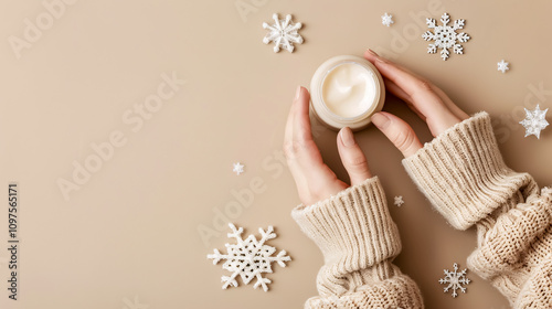 Winter Season Skincare: First-person top view photo of a woman�s hands in a knitted sweater holding a small cream jar and snowflakes on an isolated pastel beige background with empty space. photo