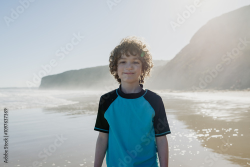 Portrait of a happy young boy with curly hair at the beach in the afternoon looking at the camera photo