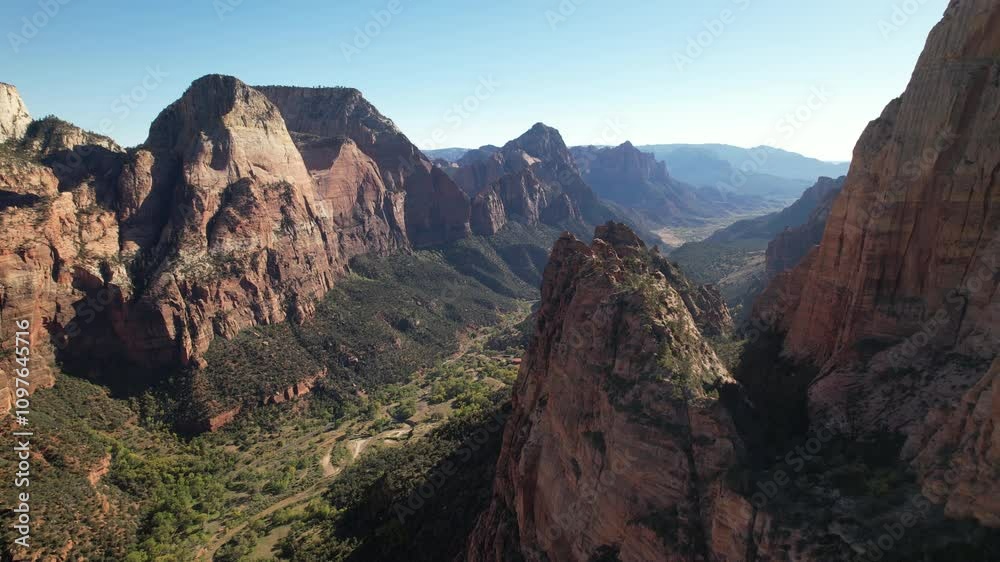 A breathtaking view of towering sandstone cliffs and lush valley below, captured mid-pan. Highlights the dramatic natural beauty and vastness of the canyon.