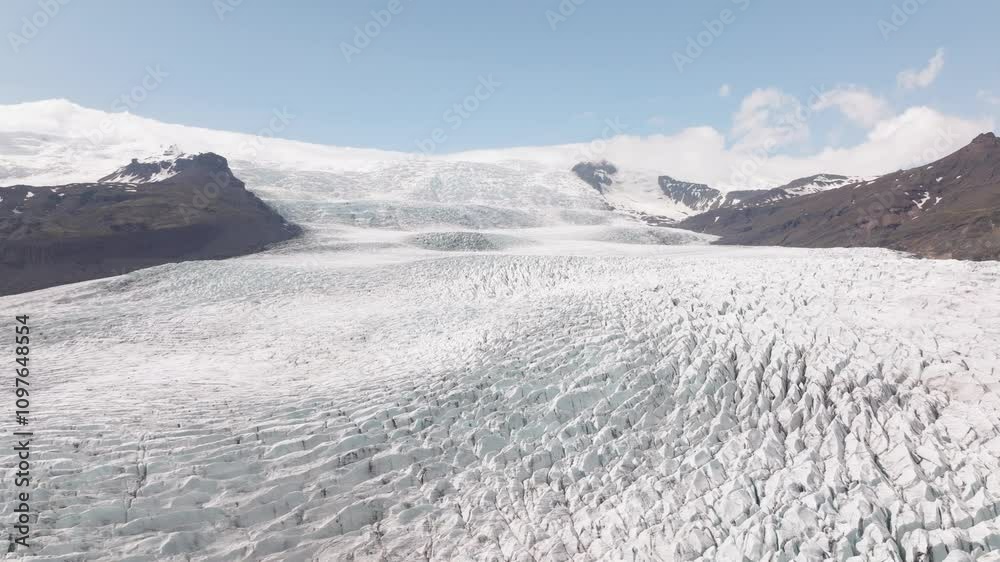 Aerial view of the expansive Fjallsjökull Glacier in Iceland, showcasing intricate crevasses and snow-covered peaks under a clear blue sky. Aerial view of the expansive Fjallsjökull Glacier in Iceland, showcasing intricate crevasses and snow-covered peaks under a clear blue sky.