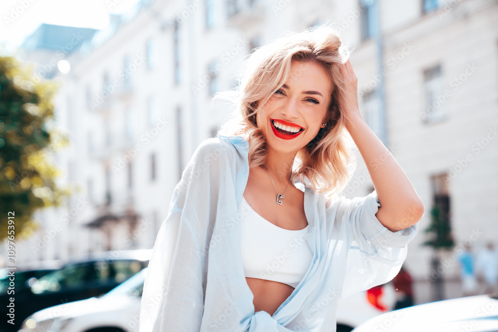 Fototapeta premium Young beautiful smiling blond woman in trendy summer clothes. Sexy carefree female posing in the street in sunny day. Positive model outdoors. Cheerful and happy, red lips. Glamorous closeup portrait