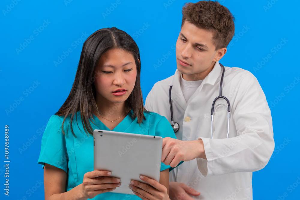 Doctor and nurse collaborating while reviewing patient information on a digital tablet. The healthcare teamwork highlights professional communication and modern technology in a clinical setting