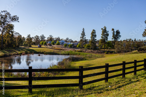 fenced off dam in green parkland beside housing suburb in Huntlee photo