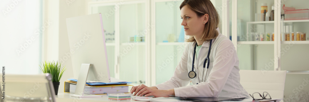 Worker in field of medicine enters patient data on computer Worker in field of medicine enters patient data on computer