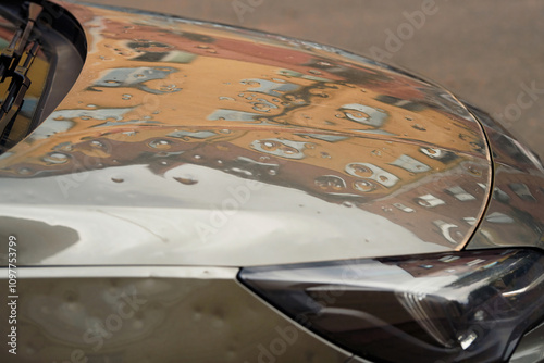 Fotografie Dented car body after hailstorm damage, hood with dents close-up,  need for repair and restoration services for weather-affected vehicles