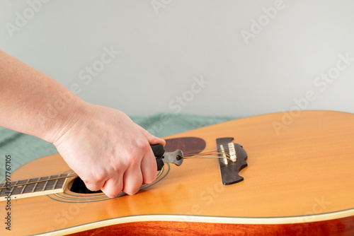 cutting old strings with pliers, removing pegs or pins from guitar bridge to replace old strings on acoustic guitar photo