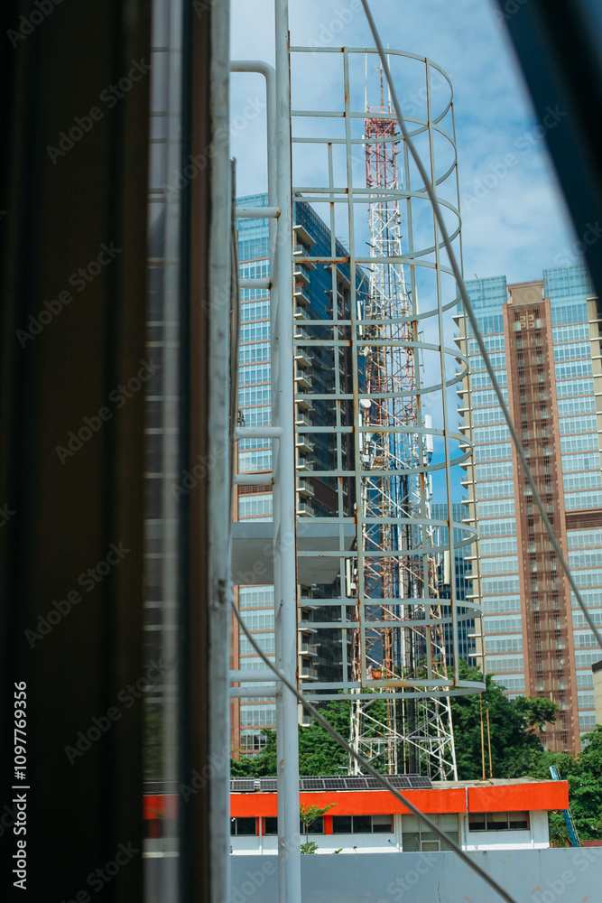 Fototapeta premium White metal fire escape attached to a wall and leading to the roof of a building.