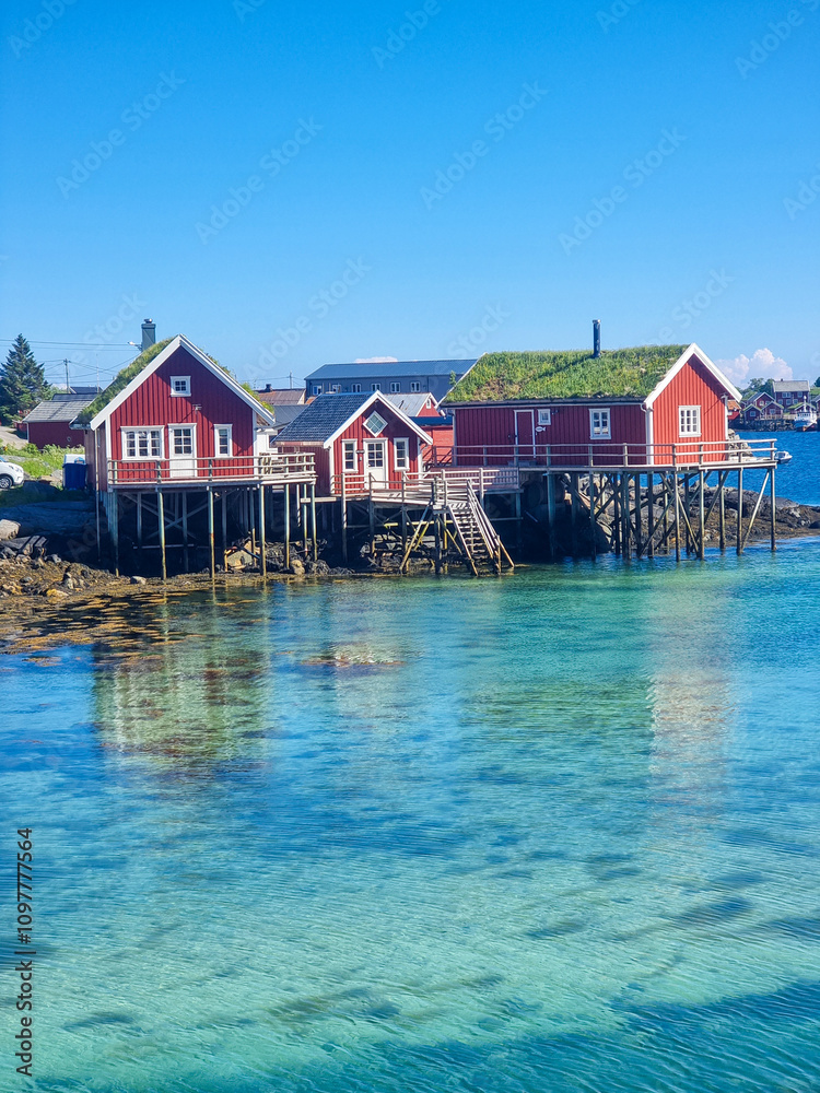 Charming red wooden houses on stilts by the crystal-clear waters of a tranquil harbor Charming red wooden houses on stilts by the crystal-clear waters of a tranquil harbor