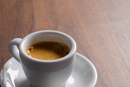 Fresh espresso in a white cup on walnut table with copy space