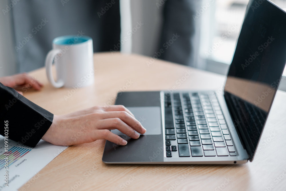 A business professional works on a laptop at a desk, accompanied by a coffee mug and document, in a modern office environment. A business professional works on a laptop at a desk, accompanied by a coffee mug and document, in a modern office environment.