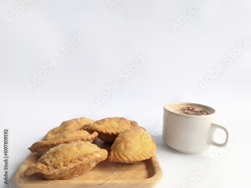 Pastel cake, a traditional Indonesian snack. Served on a woven bamboo wooden plate and a cup of black coffee. On a white background photo