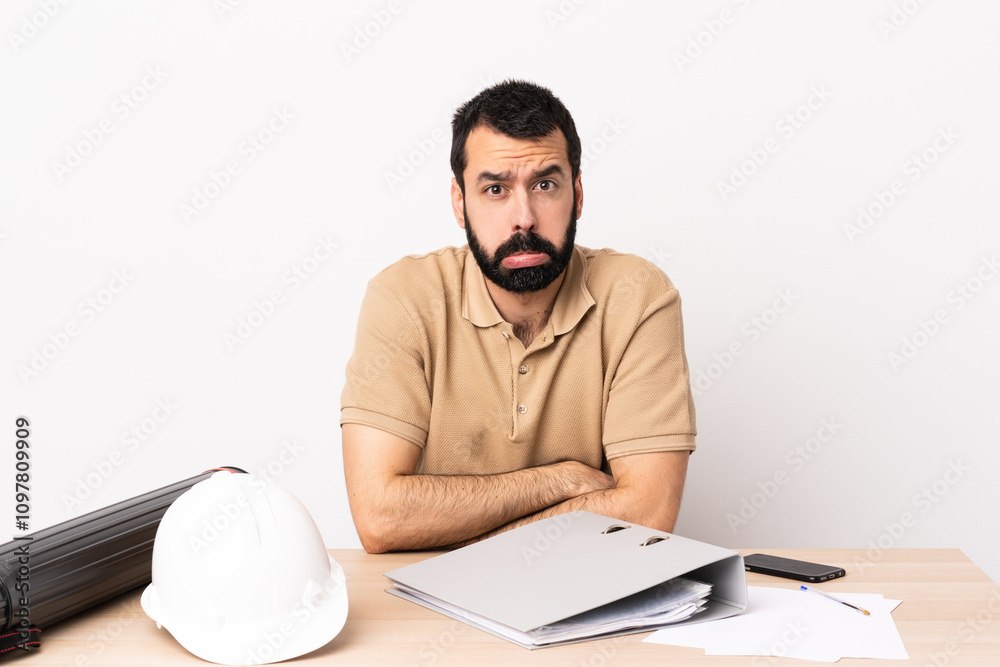 Caucasian architect man with beard in a table with sad expression. Caucasian architect man with beard in a table with sad expression.